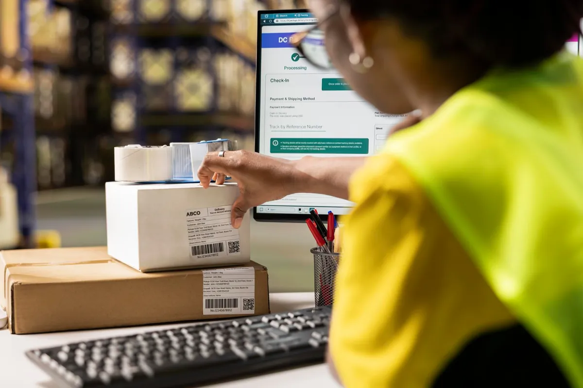 Operatrice Pakkiexpress che elabora una spedizione online con etichetta e tracking del pacco in tempo reale